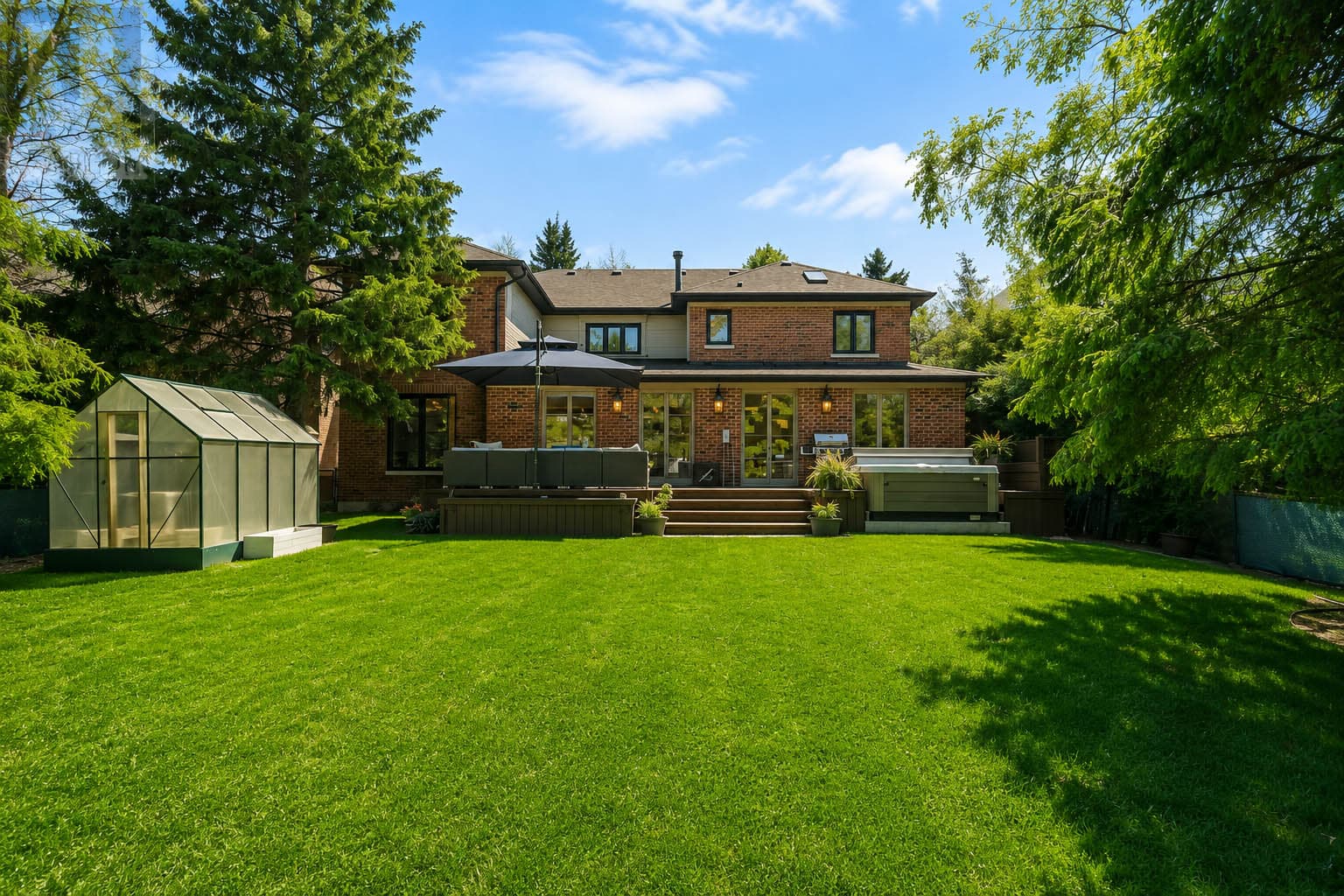 Large private backyard with greenhouse, lawn, deck and hot tub at 816 Norwick Road