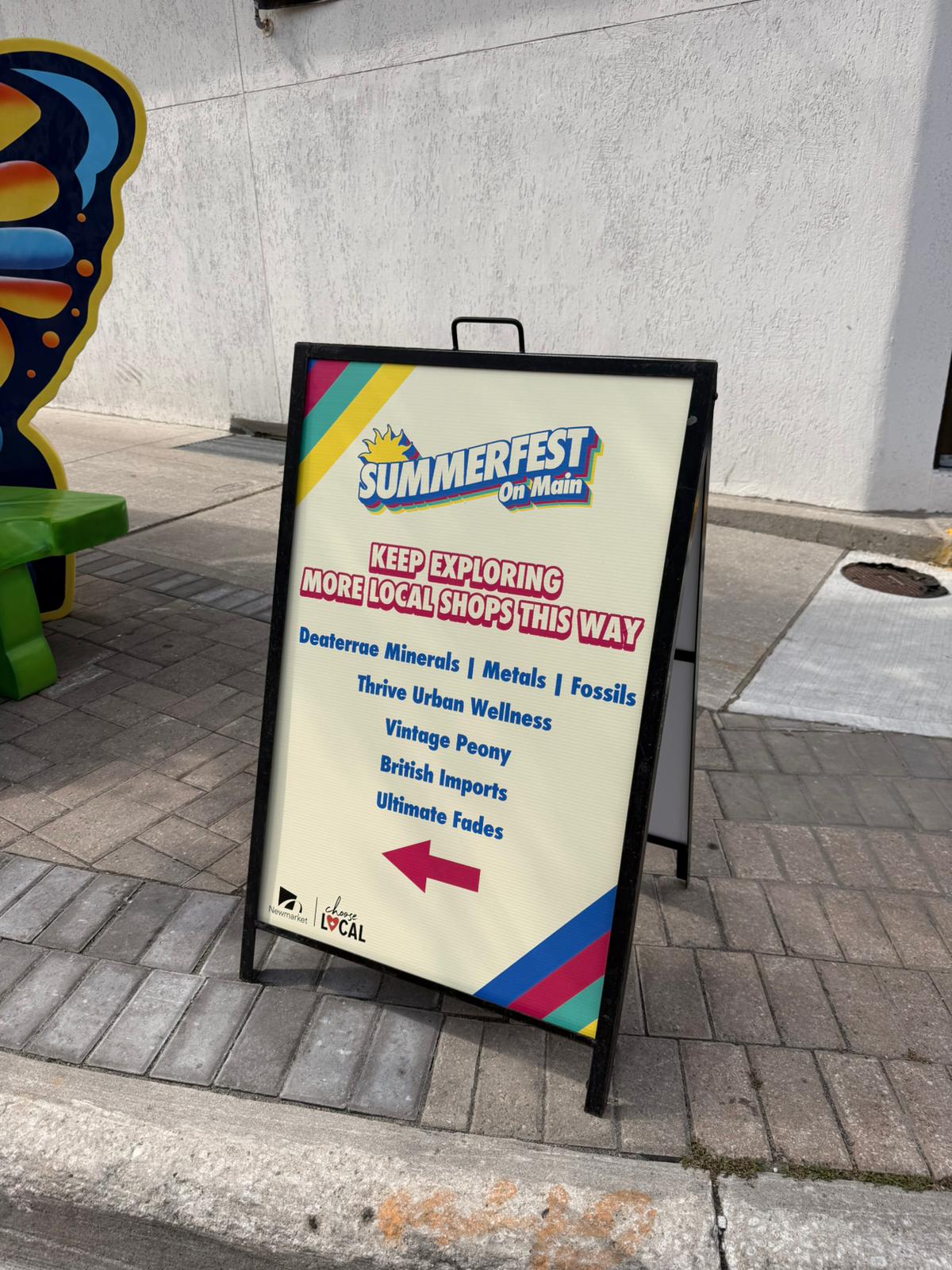 Summerfest directional sign showing live music buskers games and amenities on Main Street Newmarket
