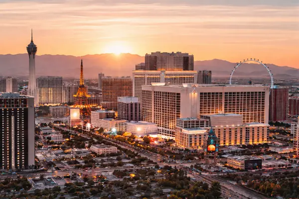 Las Vegas skyline at sunset with city lights, hotels, and surrounding mountains in the background