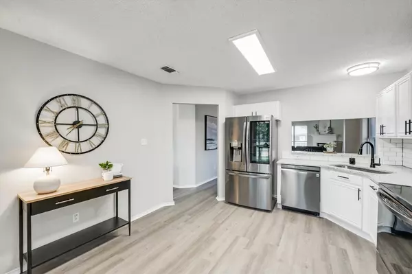 “Modern remodeled kitchen with stainless steel appliances, white shaker cabinets, subway tile backsplash, and light wood flooring in a Fort Worth home.”