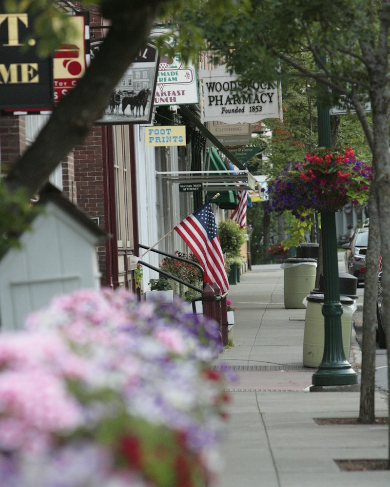 Old storefronts, hanging shop signs and a sidewalk along a small-town main street