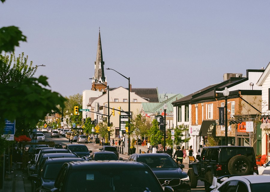 A downtown street lined with low buildings and parked cars