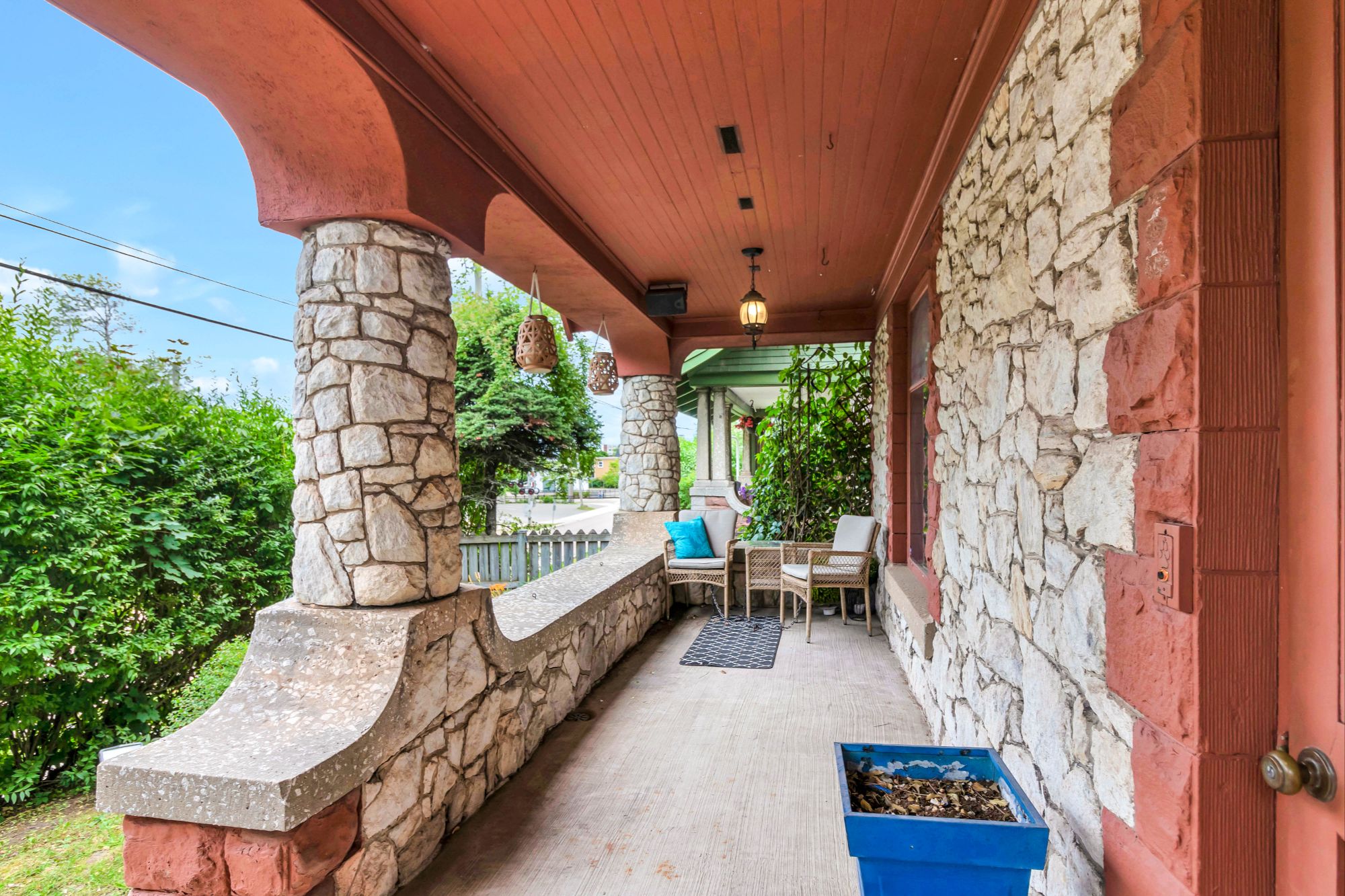 Full-width front veranda at 134 Church Street Moncton with original fieldstone pillars, lath ceiling and outdoor seating