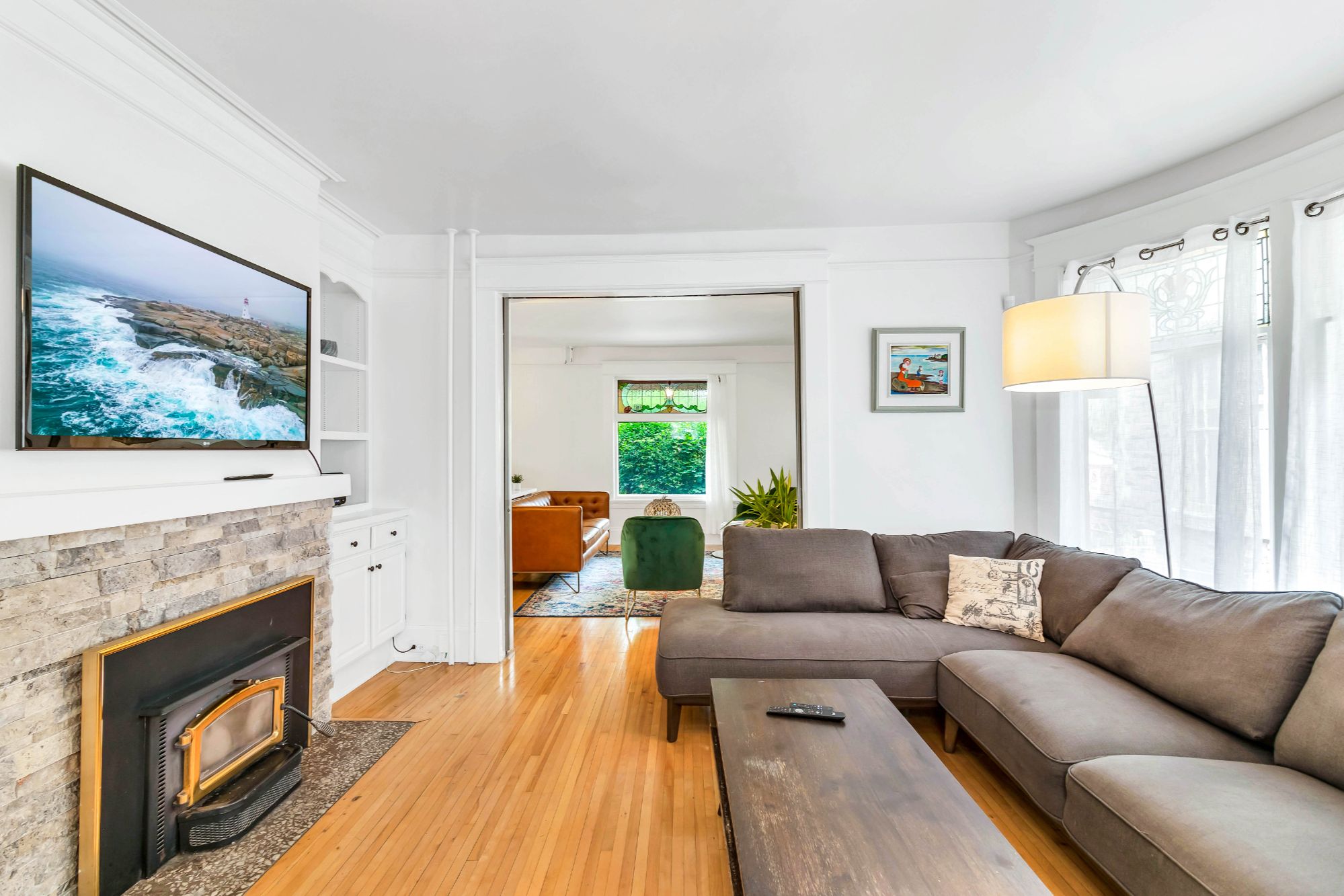 Second sitting room at 134 Church Street Moncton with stone decorative fireplace, built-in shelving and original crown mouldings