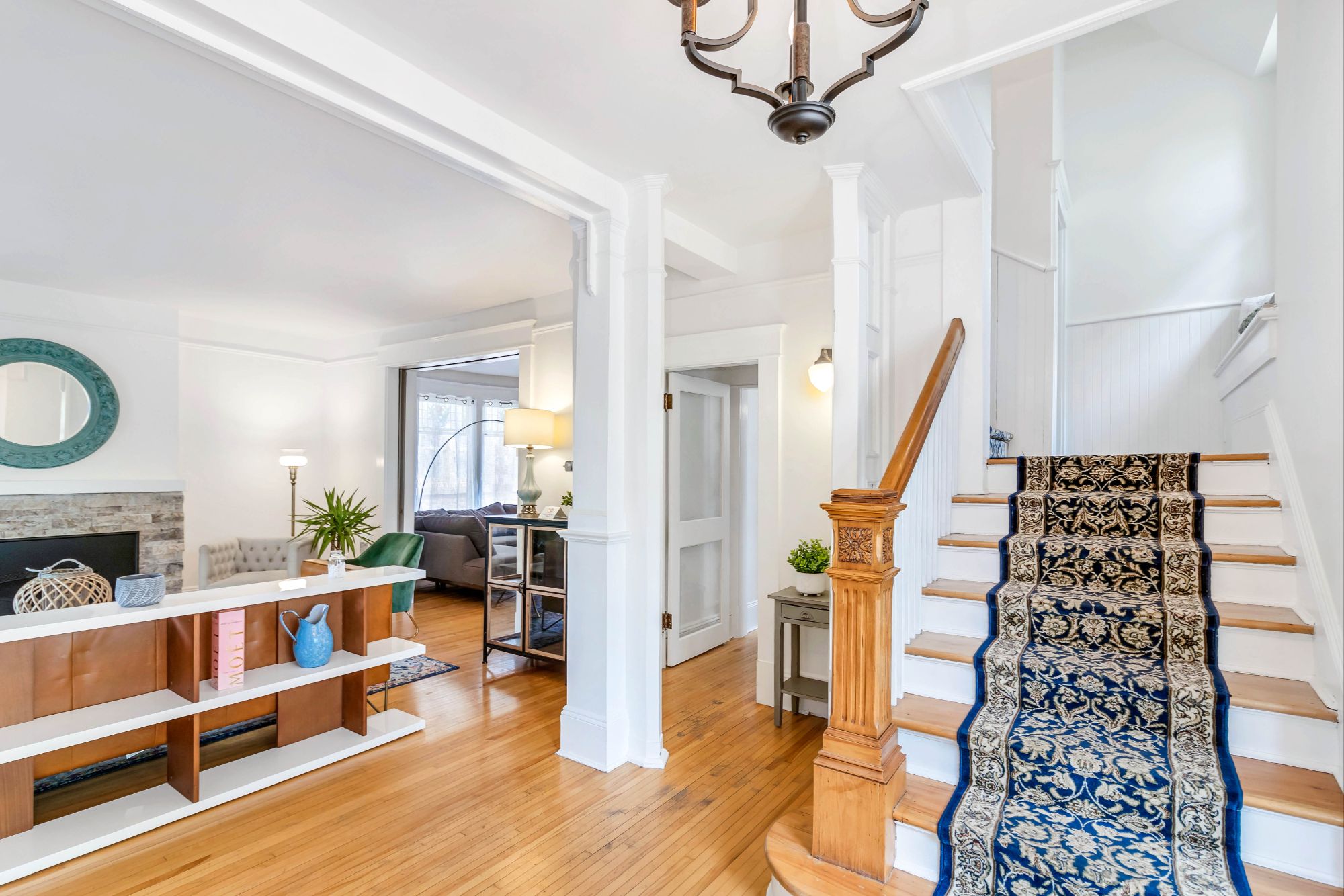Original wooden staircase at 134 Church Street Moncton with carved newel post, blue patterned runner and open view to main living area