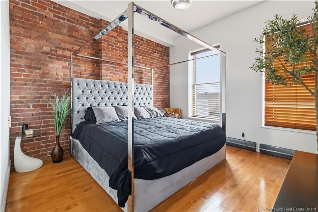 Primary bedroom with exposed brick wall at 303-850 Main Street Moncton