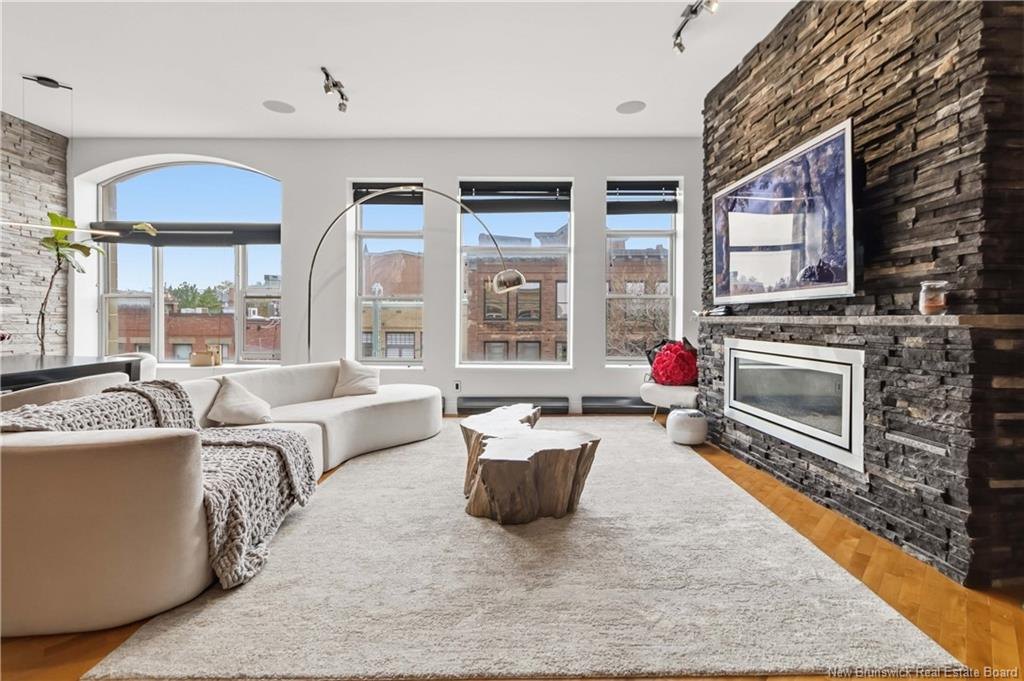 Great room at 303-850 Main Street Moncton with arched window, linear fireplace and 10.5 foot ceilings