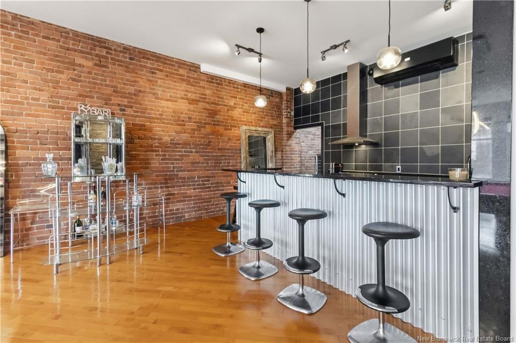 Kitchen at 303-850 Main Street Moncton with exposed brick wall and bar seating