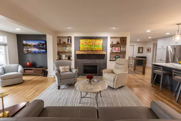 Bright modern open-concept living room with fireplace, built-in shelving, and updated kitchen — example of luxury home interior design.