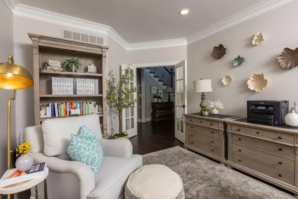 Bright home office with neutral décor, custom wood shelving, cozy seating, and contemporary design accents.