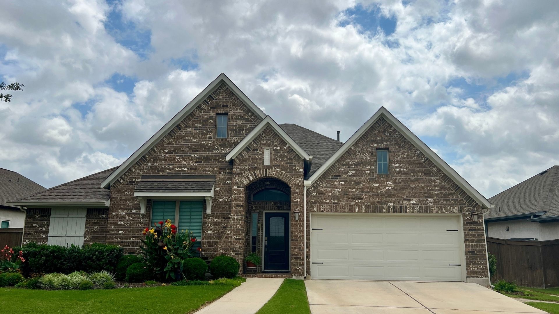 Bryson Leander Texas home featuring brick and stone exterior with mature landscaping