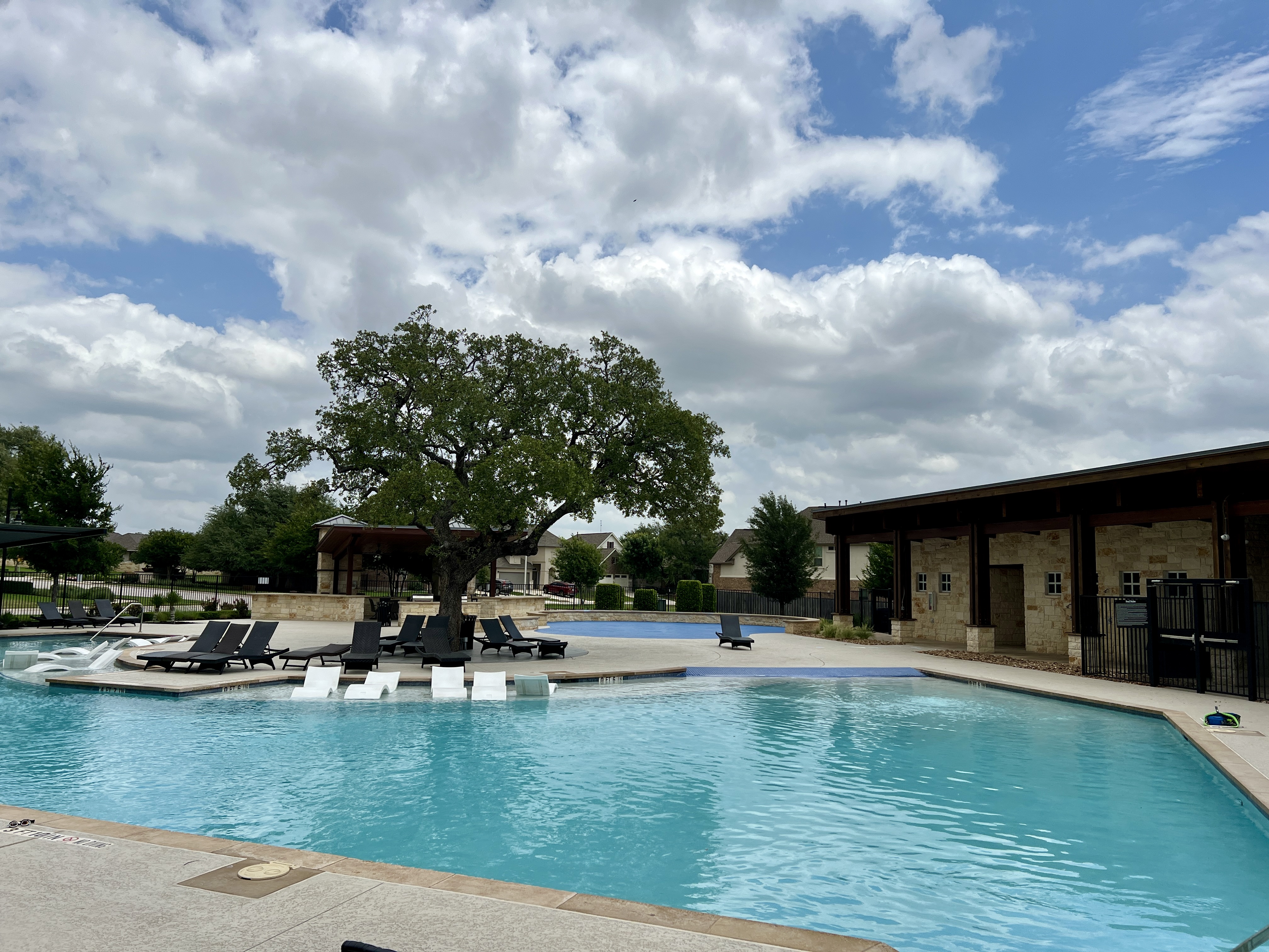 Resort-style pool at Larkspur in Leander Texas with covered cabanas, lounge seating, and community amenities for residents