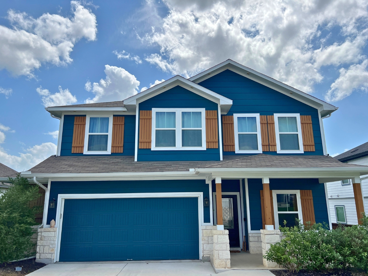 Deep blue Orchard Ridge Liberty Hill Texas home with decorative shutters, contrasting trim, and covered front porch