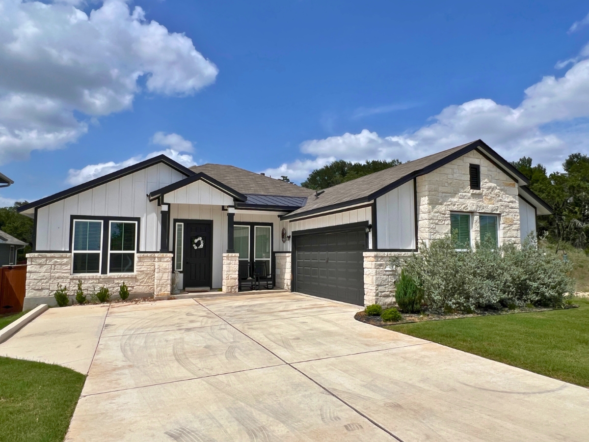 Modern farmhouse home in Orchard Ridge Liberty Hill Texas with white board-and-batten exterior, limestone accents, and contrasting black trim