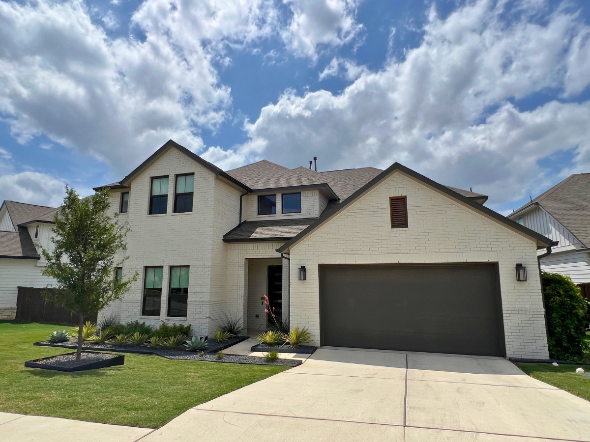 Two-story brick Orchard Ridge Liberty Hill Texas home with symmetrical windows and contemporary suburban exterior design