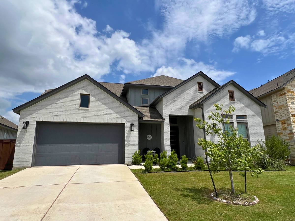 Two-story white brick Orchard Ridge Liberty Hill Texas home with dark trim accents and contemporary exterior styling