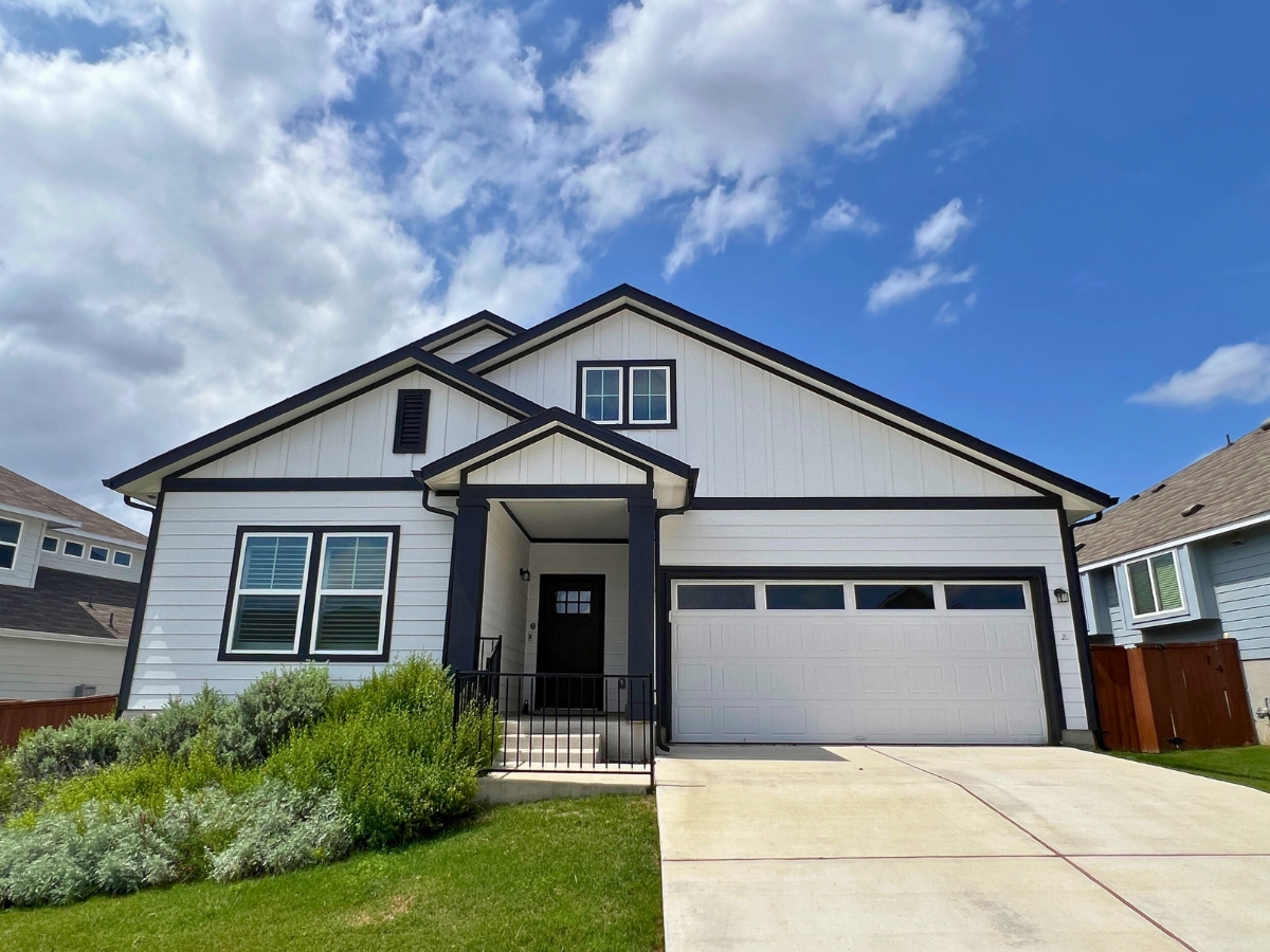 Single-story home in Orchard Ridge Liberty Hill Texas with white siding, black trim accents, and covered front entry