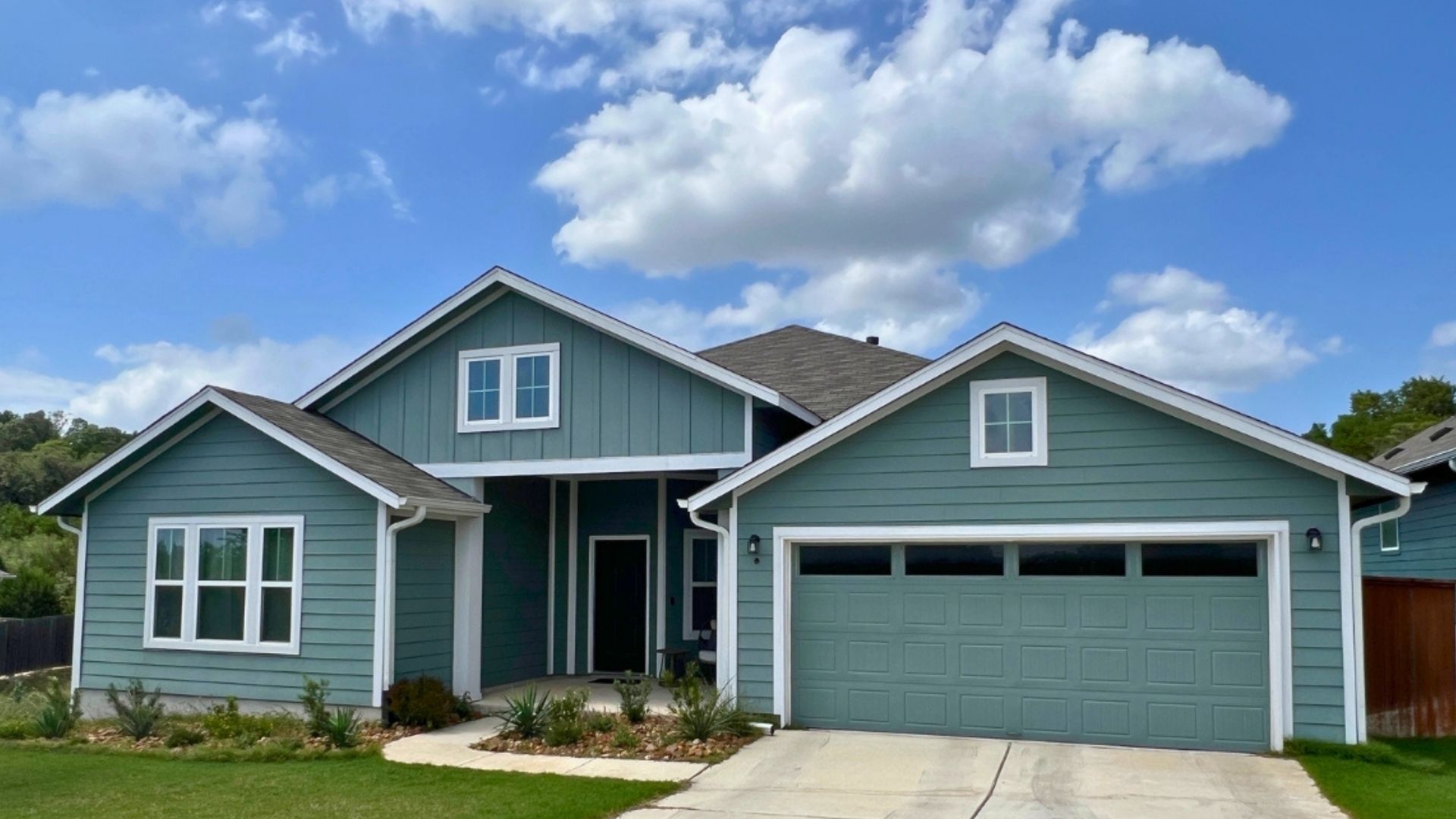 Blue-green single-story home in Orchard Ridge Liberty Hill Texas with horizontal siding, covered front entry, and attached two-car garage