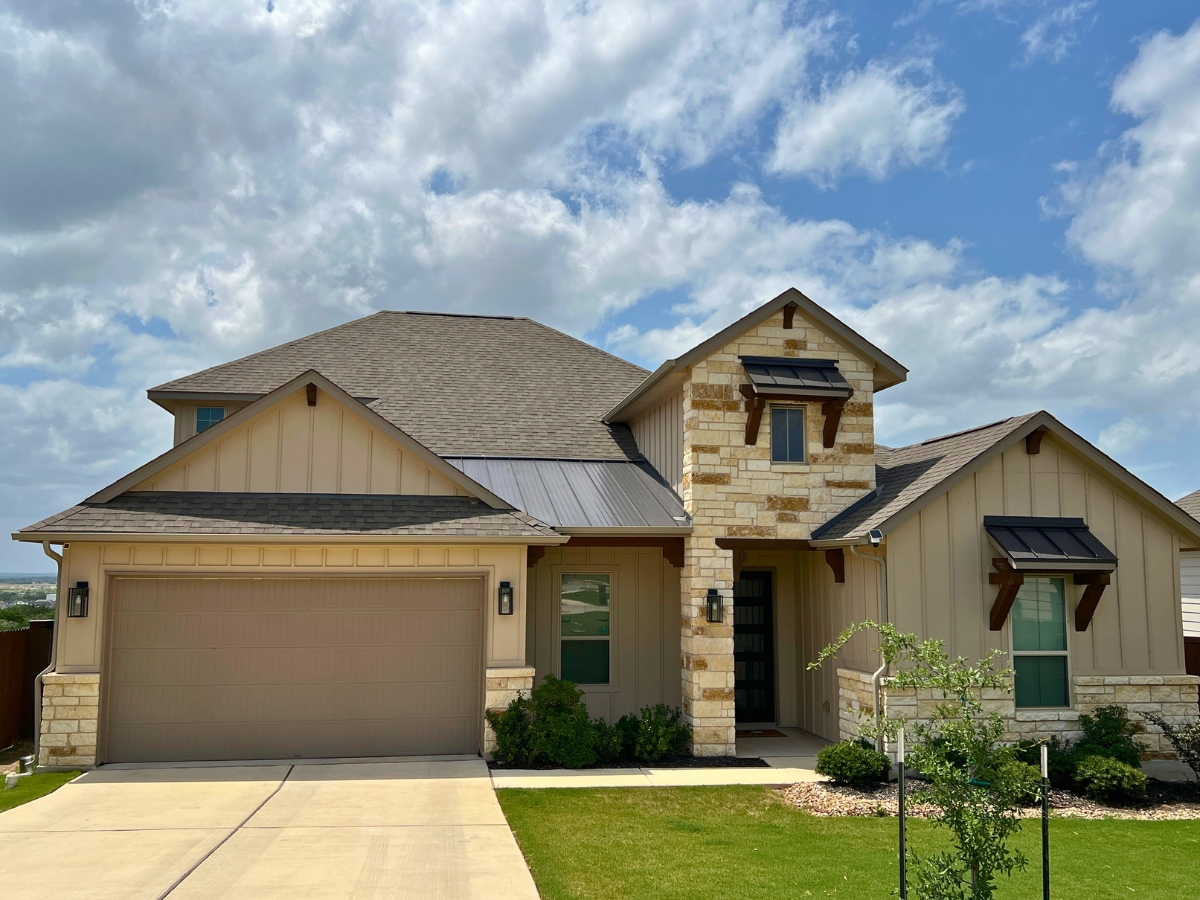 Large stone and board-and-batten home in Orchard Ridge Liberty Hill Texas with covered entry and landscaped front yard