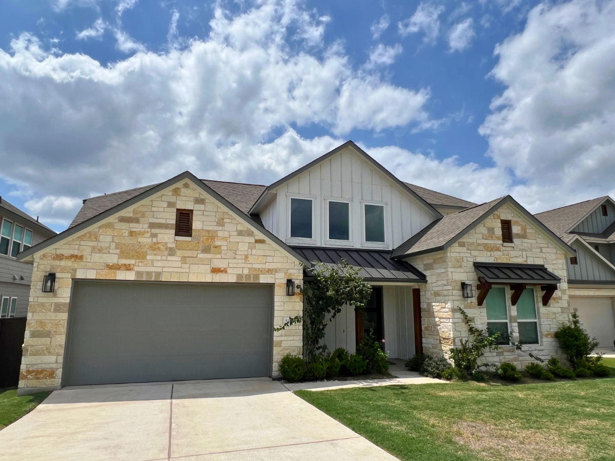 Stone and board-and-batten Orchard Ridge Liberty Hill Texas home with covered entry and farmhouse-inspired exterior details