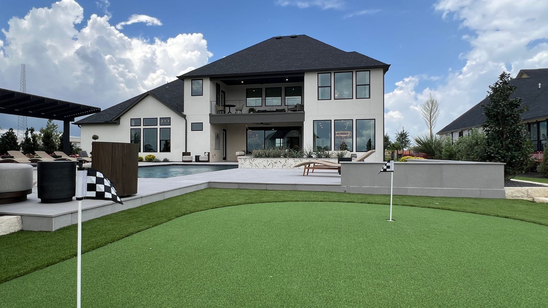 Putting green, resort-style pool, and second-story balcony at the Drees McKennan model home in Hilltop Ranch, Leander, Texas