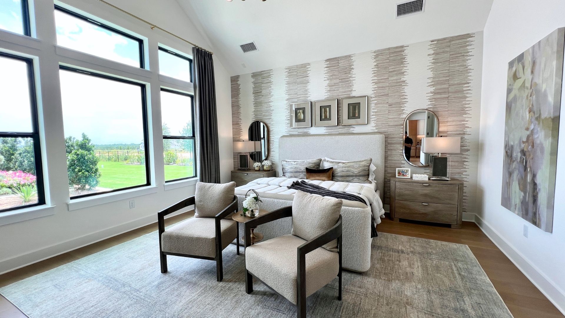 Primary bedroom with large windows and backyard views in the Drees McKennan model home at Hilltop Ranch in Leander, Texas
