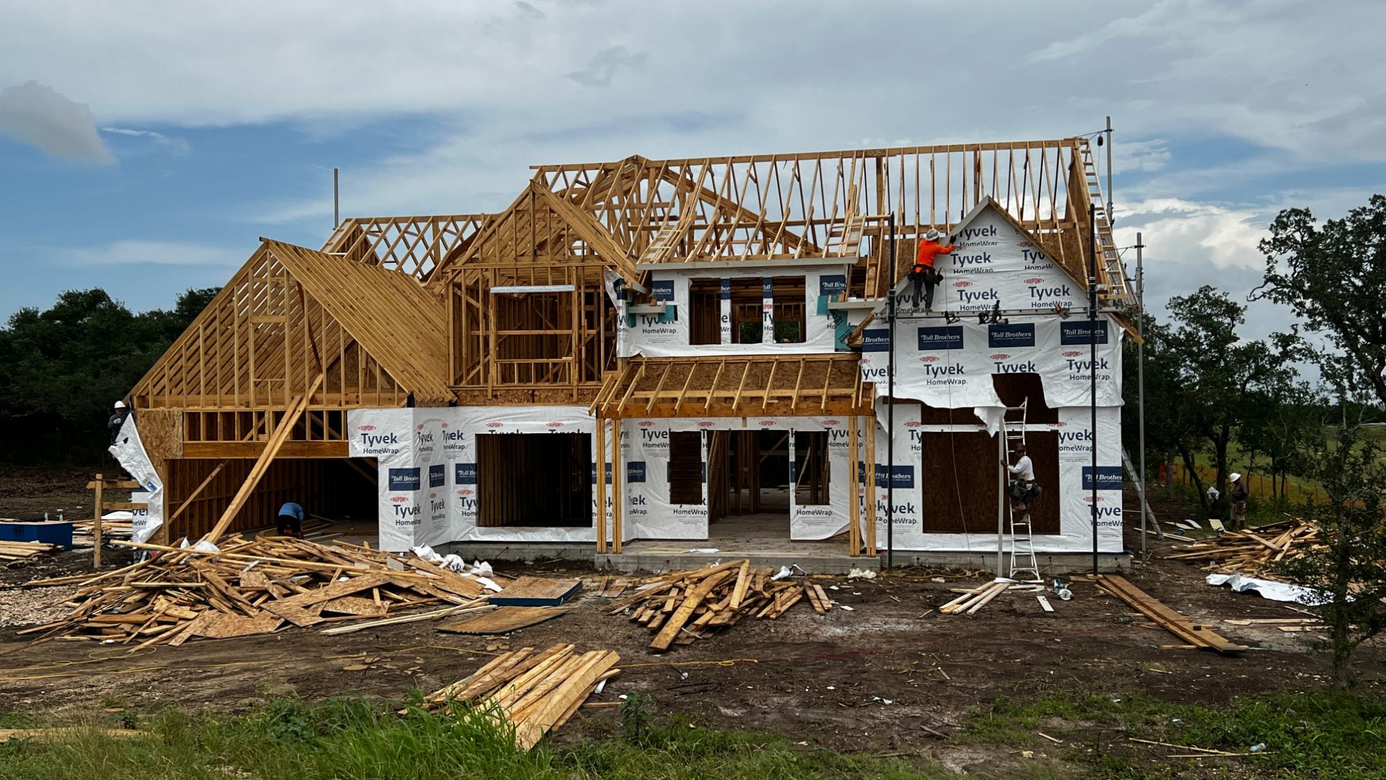 Toll Brothers home under construction surrounded by mature trees at Woodland Estates in Leander, Texas