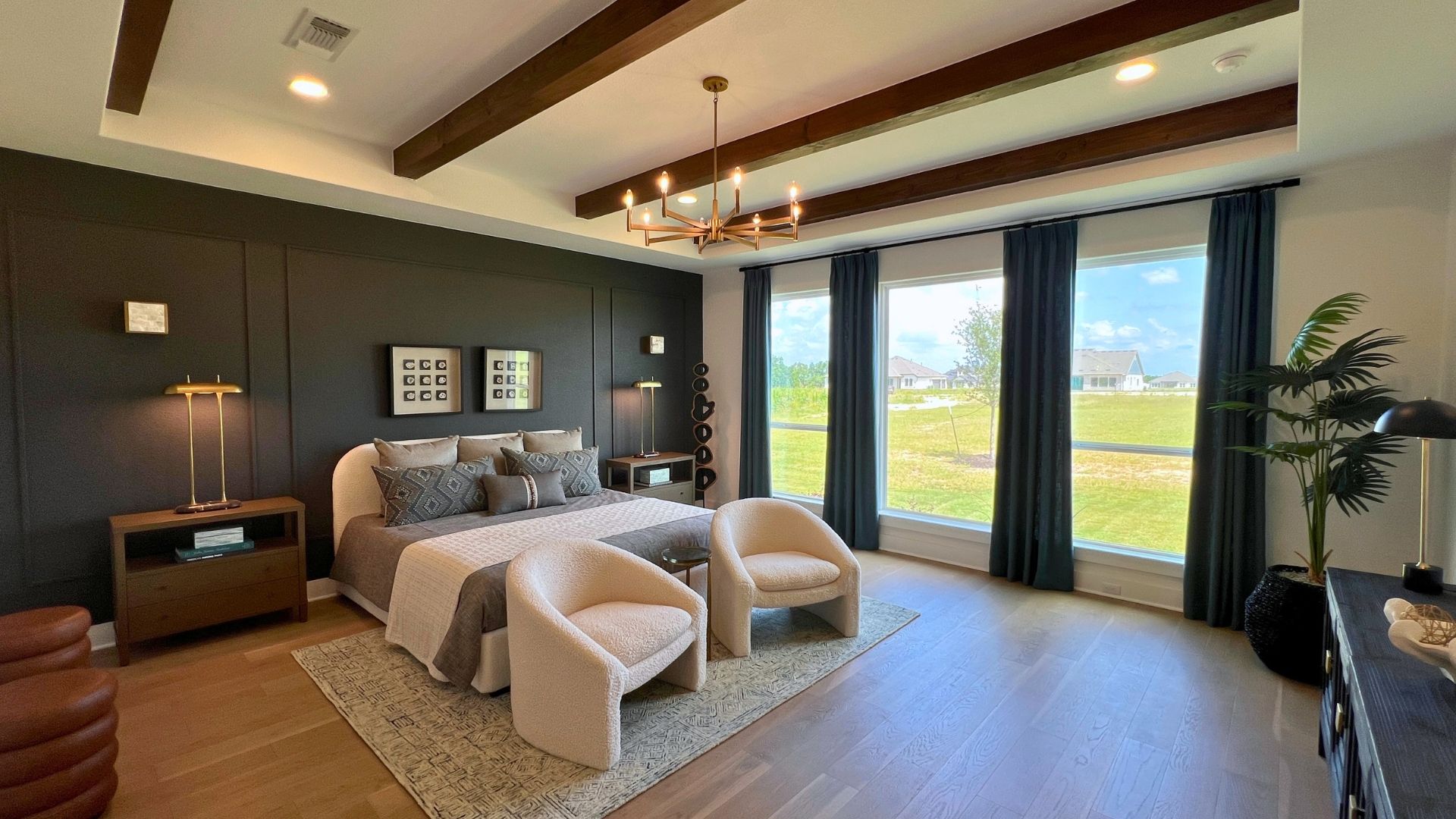 Primary bedroom with wood beam ceiling and abundant natural light in the Giddens Kerrville model home at Leander Estates in Leander Texas