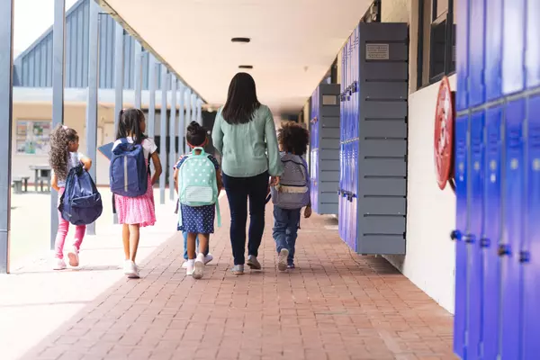 a-biracial-teacher-walking-with-students-in-school-2025-04-04-18-09-49-utc