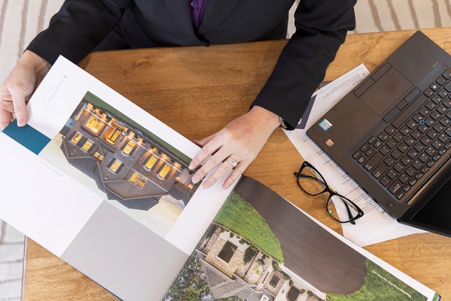 Kim Phelps reviewing property marketing materials beside a laptop at a wooden table