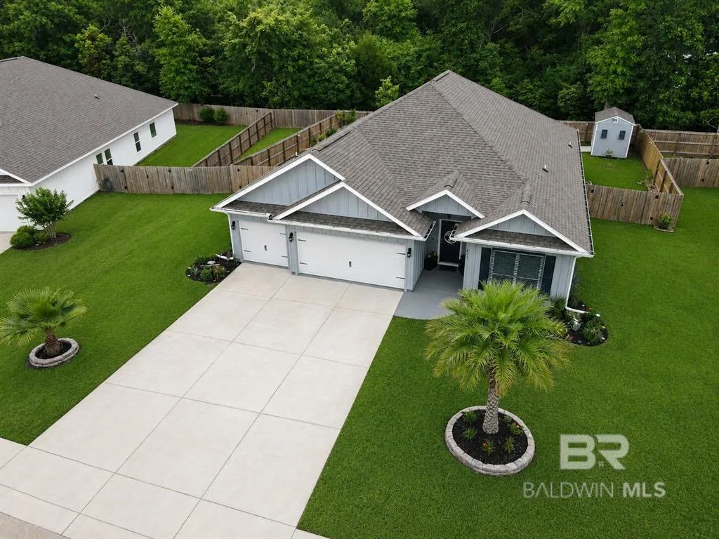 Modern pool home in Foley Alabama with covered patio, fenced backyard, and palm trees in a quiet suburban neighborhood