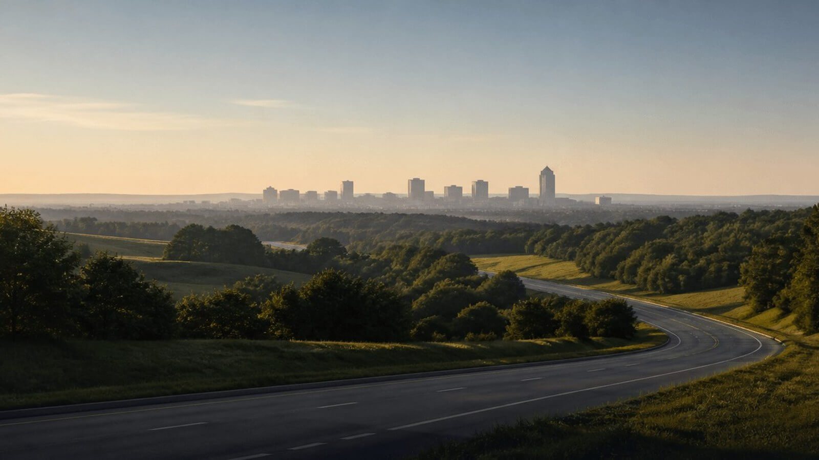Highway curving toward a distant skyline at dawn
