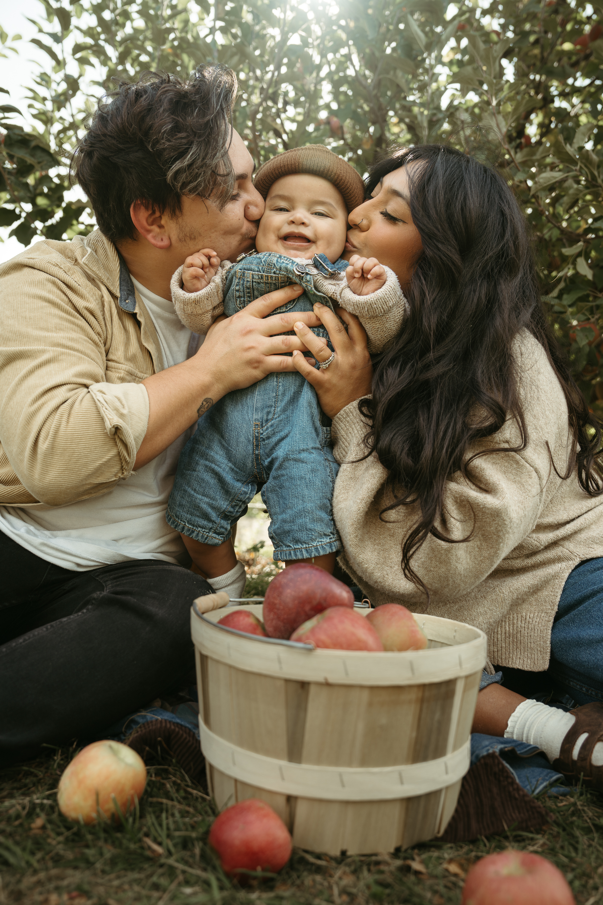 Jen and Frankie Gilmore kissing their son Cisco while apple picking