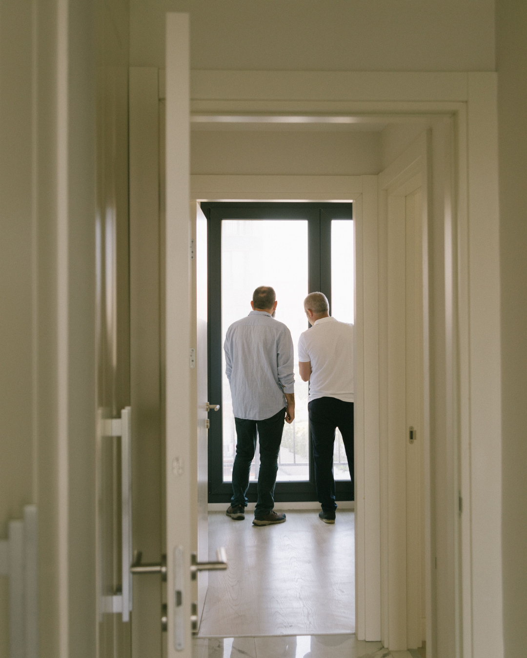 Two people walking through a home's interior hallway while evaluating rooms and layout during a property viewing.
