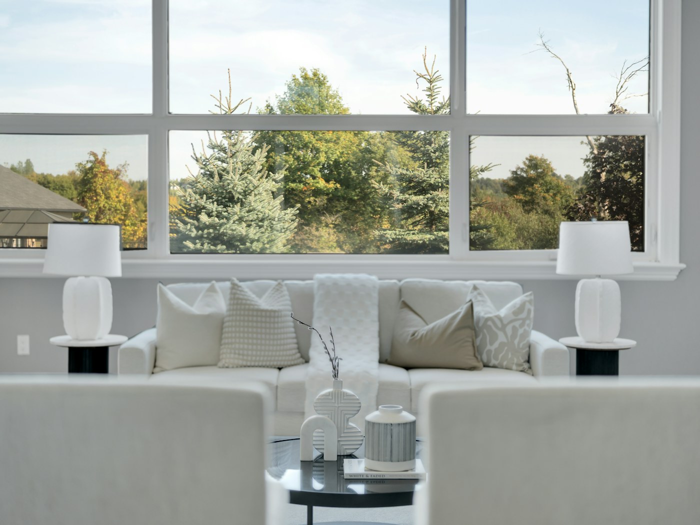 A bright living room with large windows looking out onto mature trees