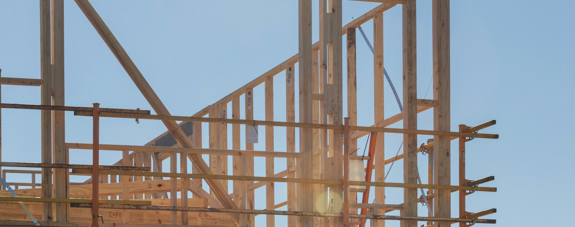 New houses under construction with wooden framing against a clear sky