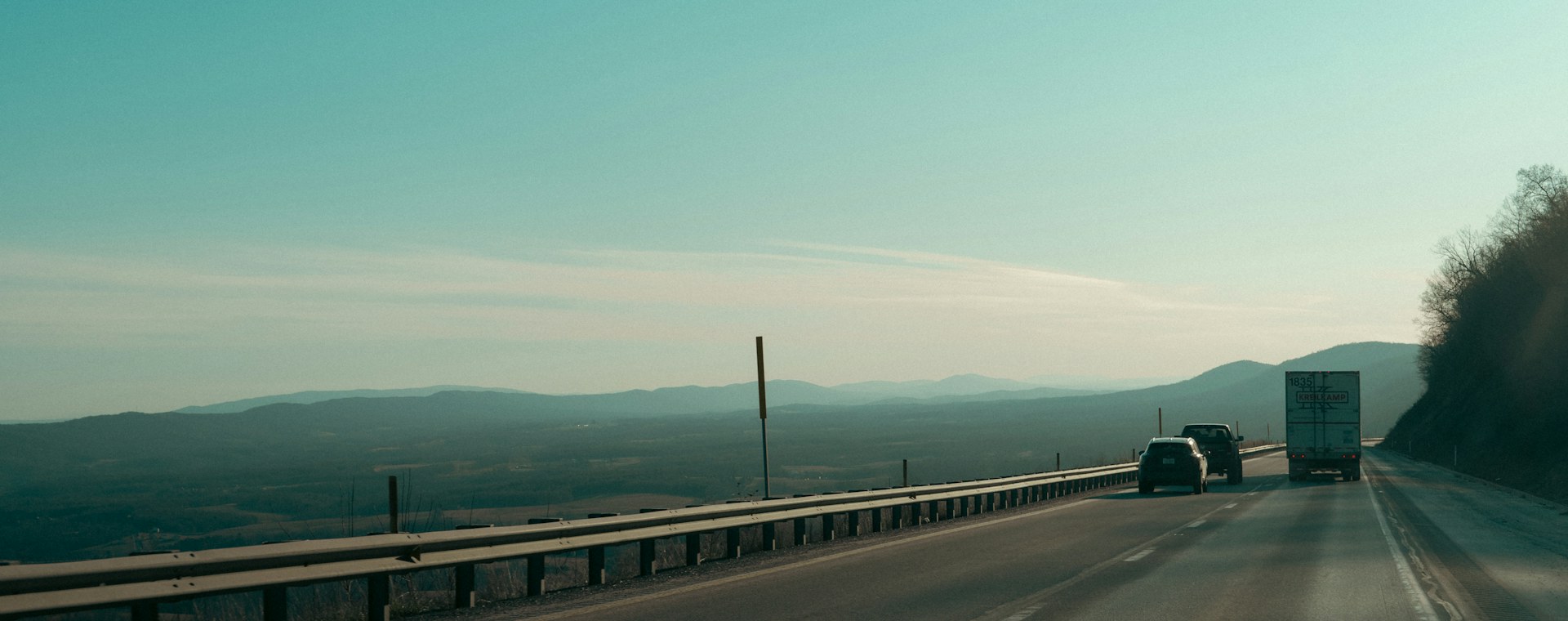 Trucks driving on a highway toward distant hills