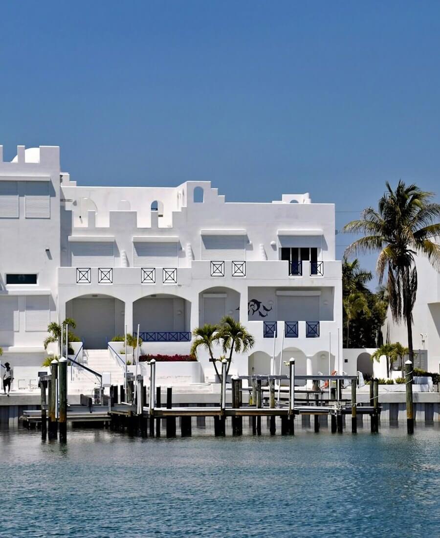 Modern white waterfront homes lining a Florida canal with palm trees