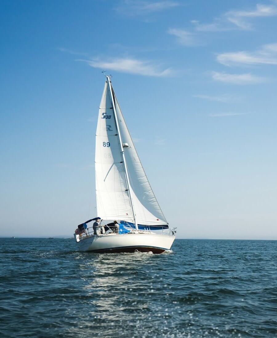 White sailboat under full sail on calm blue Gulf of Mexico water