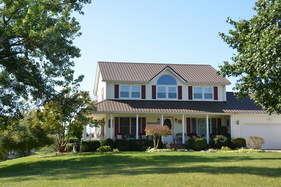 Two-story home with a brown metal roof on a lawn