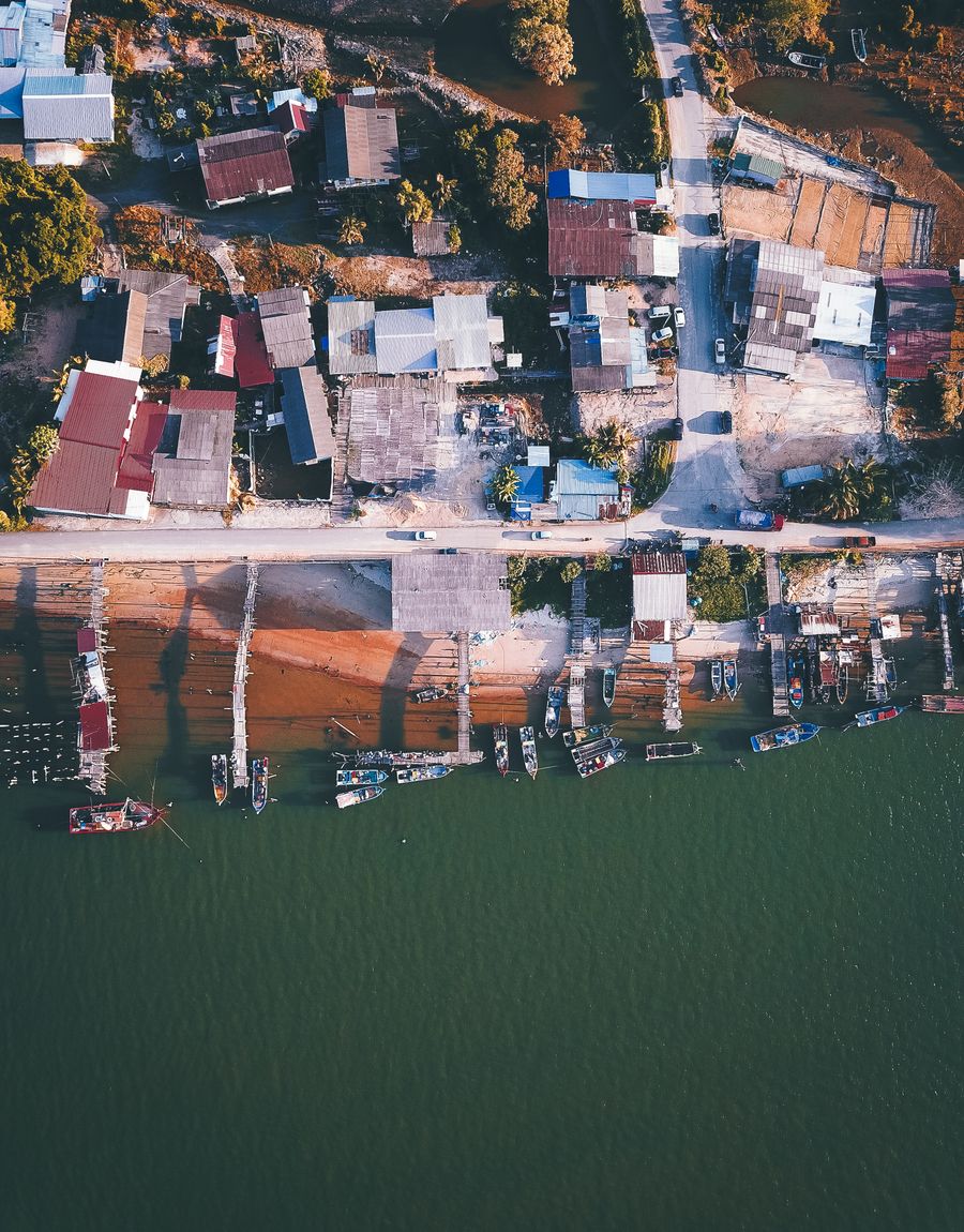 Aerial view of coastal village houses along a calm shore with moored boats