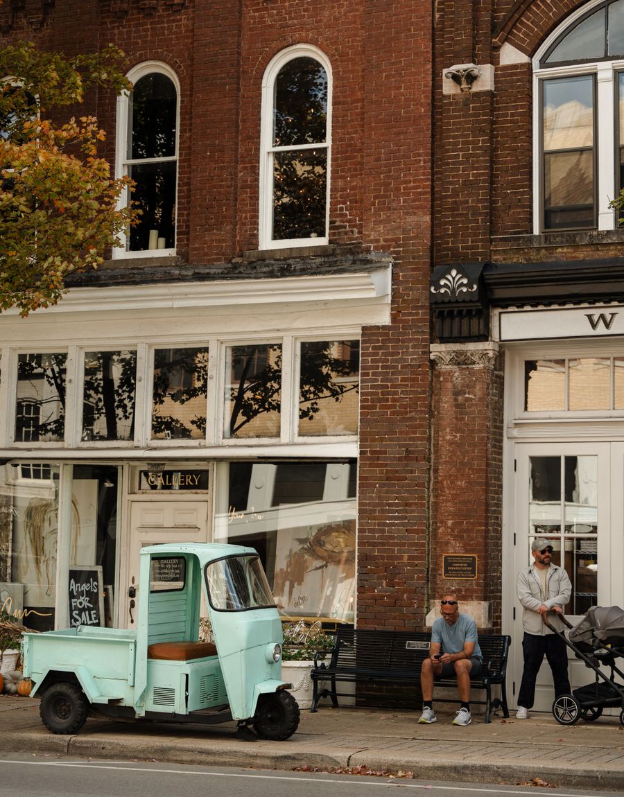 A small-town street with a red-brick building and a vintage vehicle