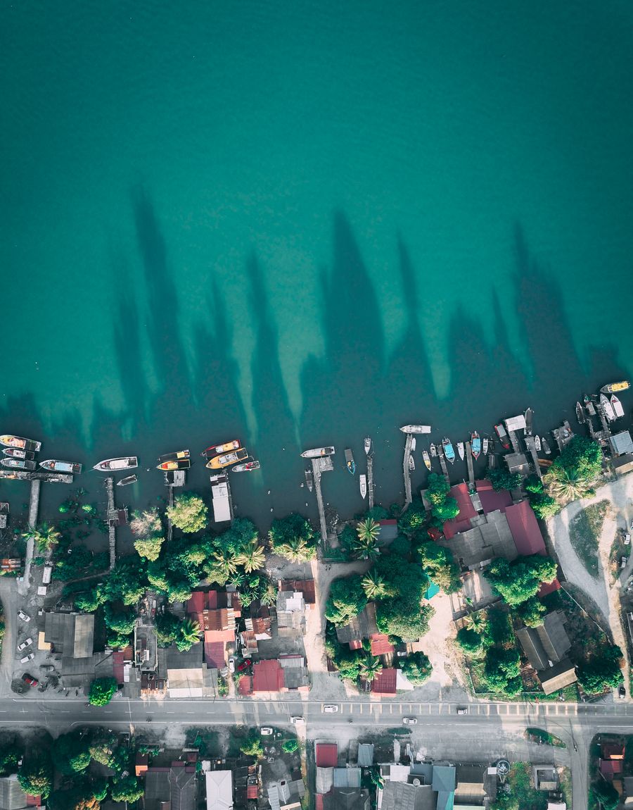 Aerial view of a small coastal town on calm water with piers and moored boats