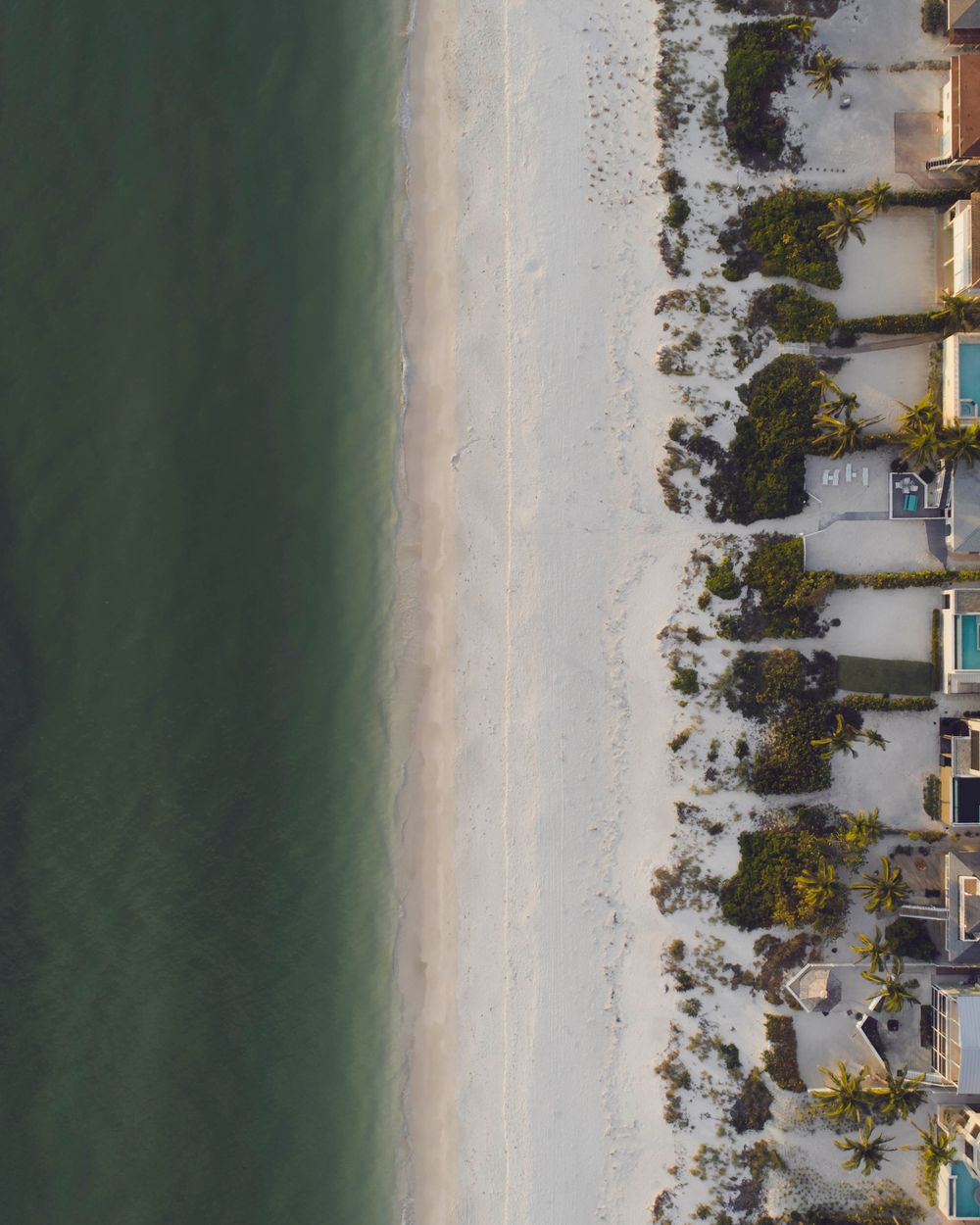 Aerial view of oceanfront homes along a white-sand beach