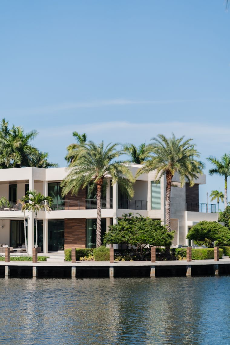 A modern waterfront villa framed by palm trees