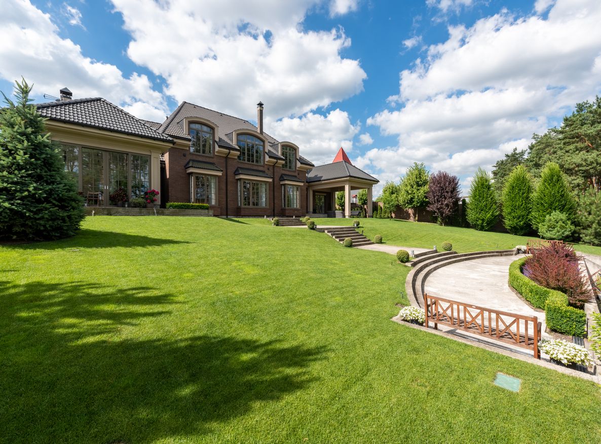 A brick estate with a manicured lawn and garden