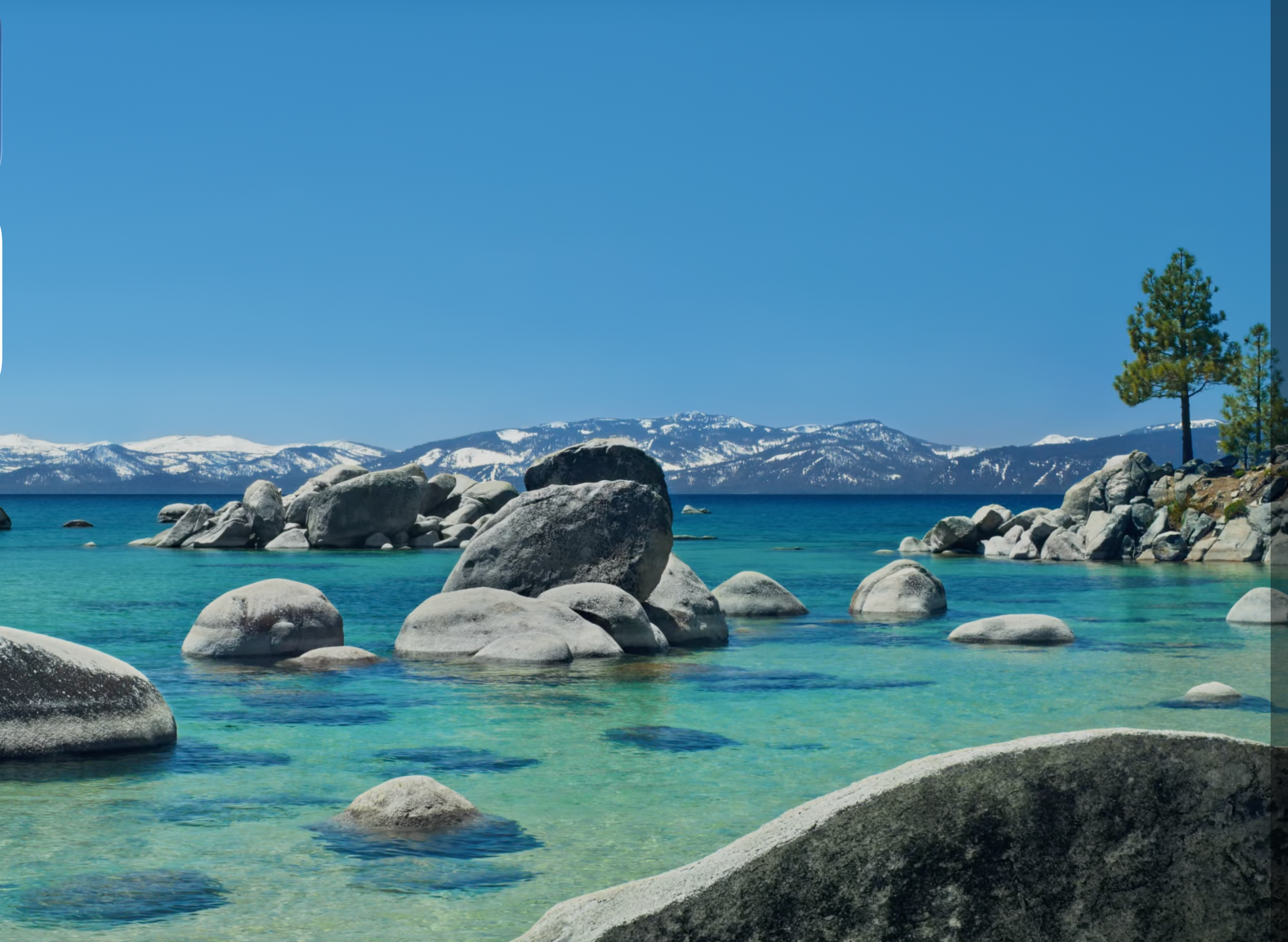 Sand Harbor, Lake Tahoe — granite boulders in clear turquoise water with the Sierra Nevada in the background