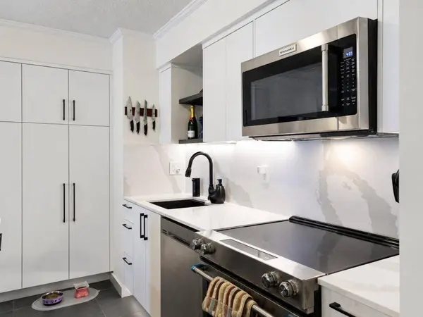 Custom renovated kitchen with large quartz island, bar seating, full-height cabinetry, stainless steel appliances and exceptional storage.
