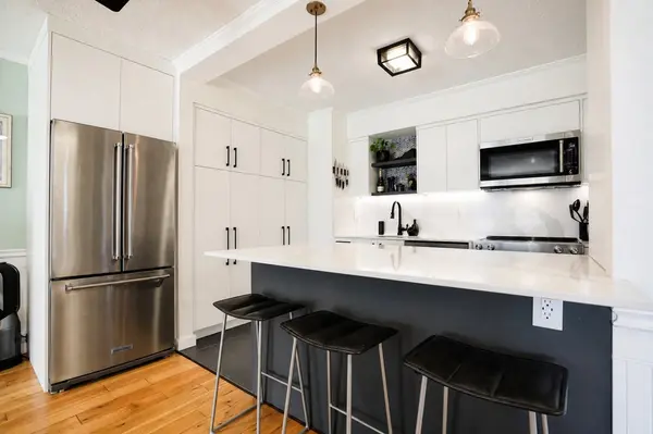 Custom renovated kitchen with large quartz island, bar seating, full-height cabinetry, stainless steel appliances and exceptional storage.