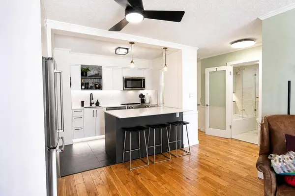 Renovated open-concept kitchen with large island and bar seating, great for entertaining, with views toward Vancouver from 303-441 E 3rd Street, North Vancouver.